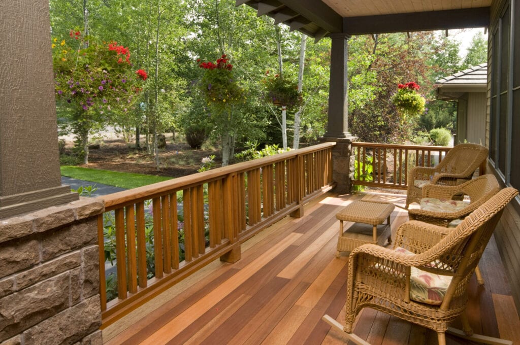 Dit veelkleurige hardhouten voordek, met rieten stoelen, geeft u een prachtig uitzicht op de tuin in de ochtend.