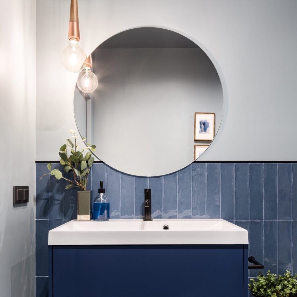 Ontworpen badkamer met stijlvolle blauwe kast, blauwe wandtegels en grote ronde spiegel betaalbare badkamerinrichting 