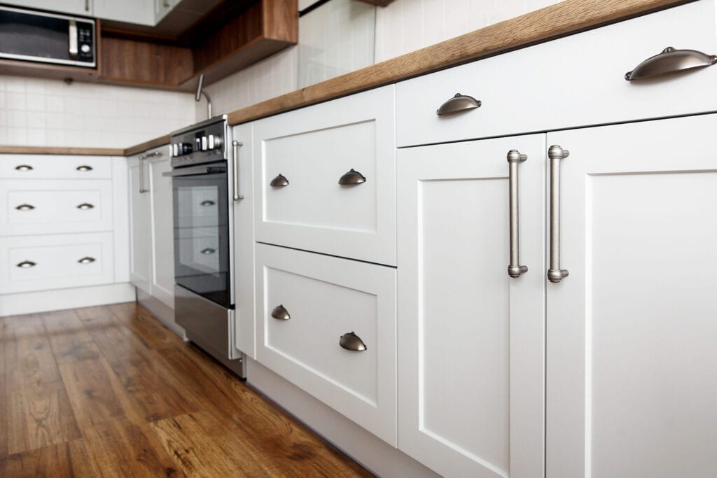 Close-up van witte keukenkastjes met houten aanrechtblad en messing handgrepen