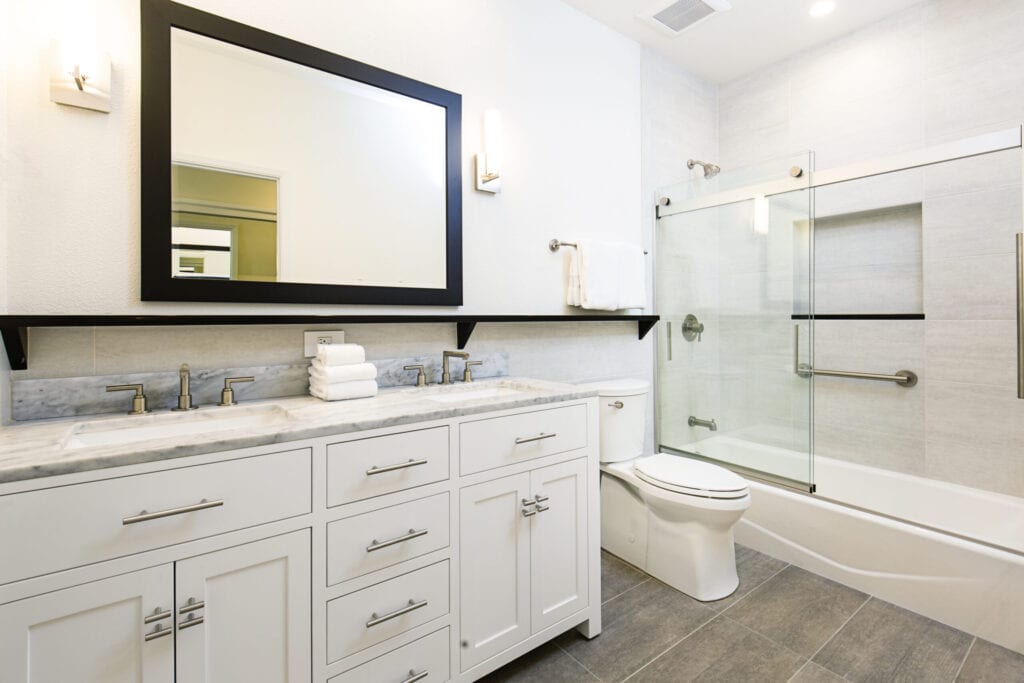 Een eigentijds modern badkamerontwerp. met een bad met glazen douchecabine, toilet en zijn en haar dubbele wastafel.