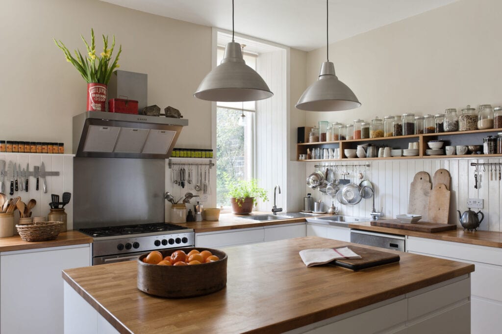Ruime keuken met open rekken en massief eiken werkbladen. De hanglampen en units zijn beide van Ikea